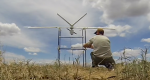 A closeup photo of an individual working on a UAS in nature.