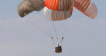 Photo of paracargo attached to parachutes floating to the ground.
