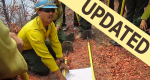 Photo of a firefighter using a map on the ground to explain the situation to those around him with updated banner in upper right corner.