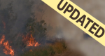 Photo of heavy smoke with truck barely visible coming down road. With "UPDATED" banner.