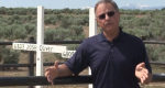 Man standing in front of two white cross markers.